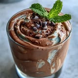 Creamy chocolate mint protein shake with frozen banana, blended to perfection for a refreshing post-workout treat.  