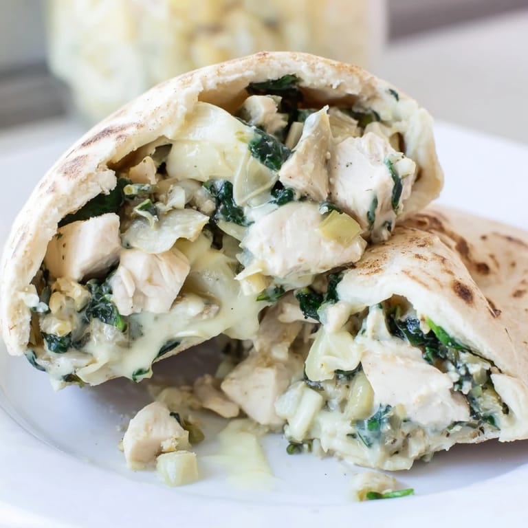 Close-up on Spinach Artichoke Chicken Stuffed Pita, golden-brown pita bread stuffed with a vibrant green and cheesy Mediterranean-American lunch filling.