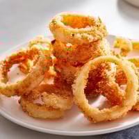 Golden, crispy onion rings freshly fried and ready to be dipped, perfect appetizer.