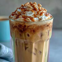 Creamy Iced Vanilla Bean Frappuccino with fluffy coconut whipped cream, perfect for a refreshing vegan coffee treat.